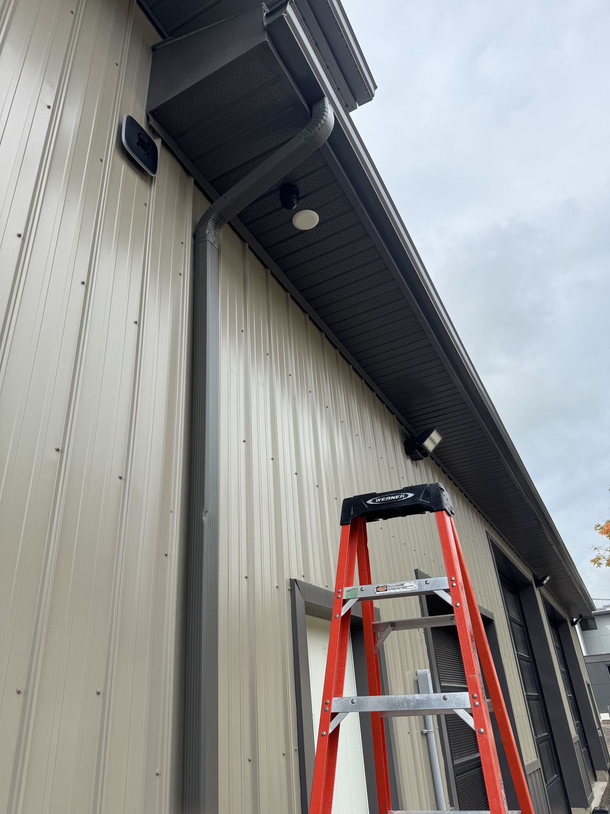 Outdoor siren, camera and floodlight mounted together on a commercial building