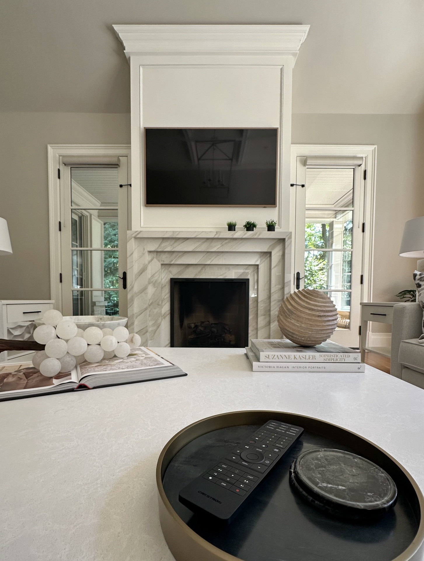 Living room fireplace with mounted TV and Crestron remote control