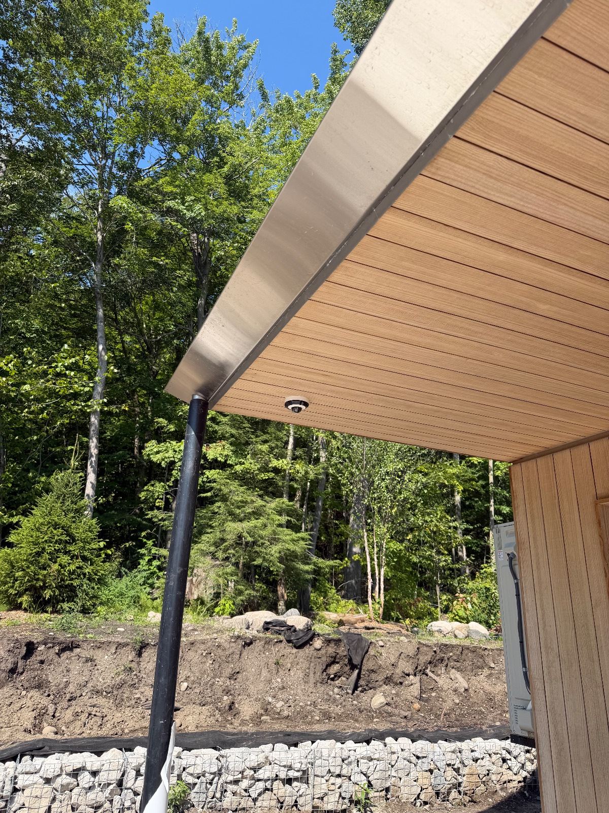 Dome camera in a cedar soffit overlooking a wooded lot
