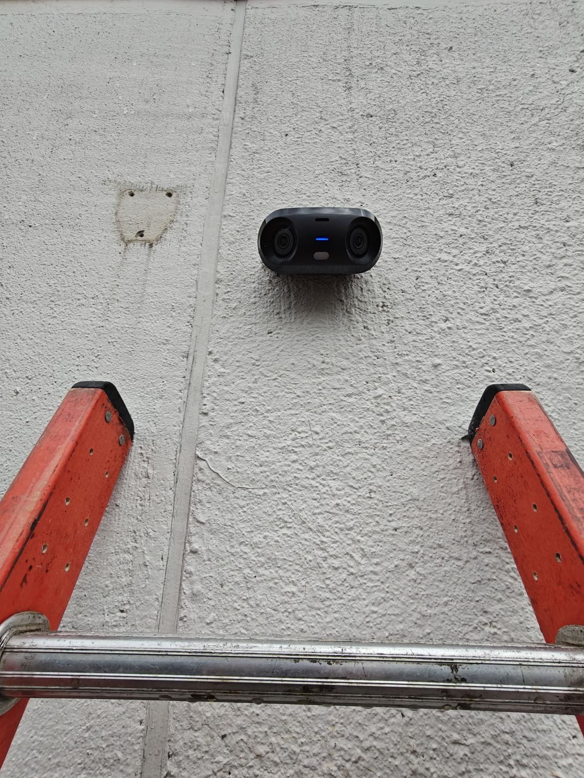 Dual-lens security camera mounted on a stucco wall