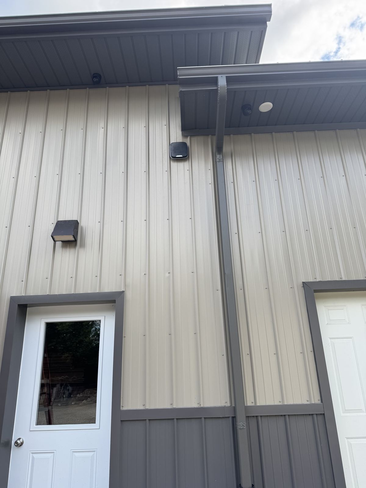 Ajax outdoor siren between two soffit cameras over a service door