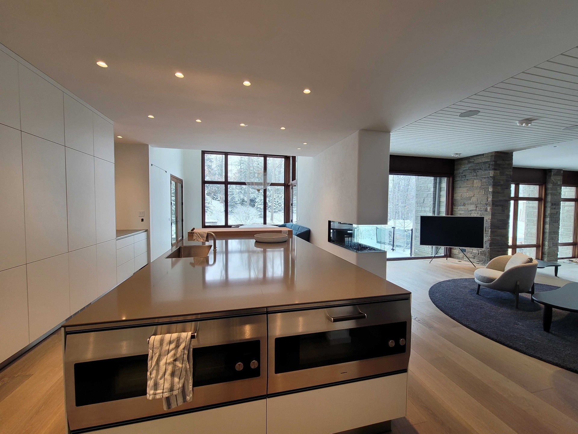 Open concept modern kitchen and living room with integrated audio and easel TV