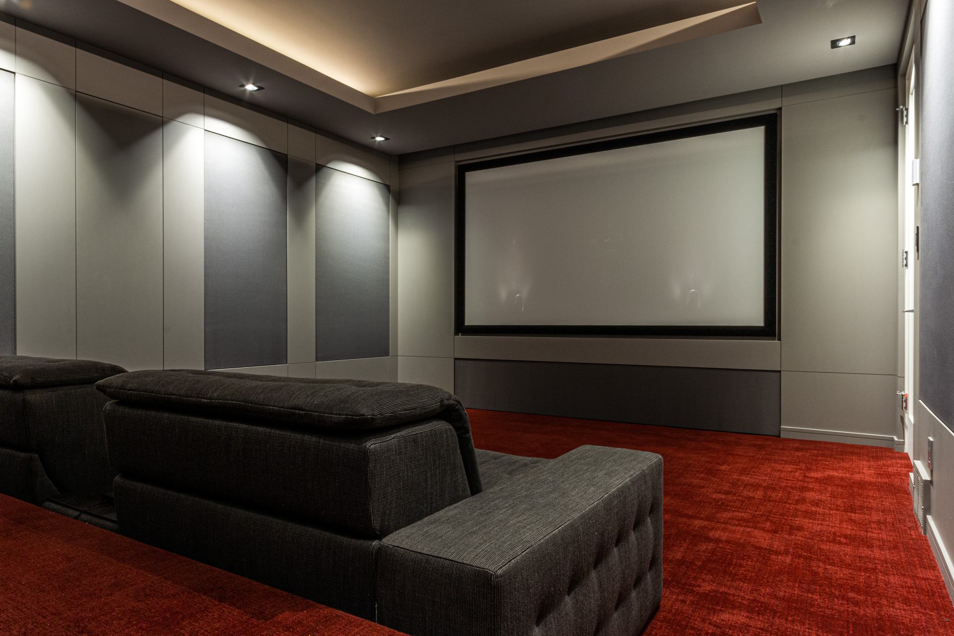 Dedicated home theatre with acoustic panels, projection screen and red carpet